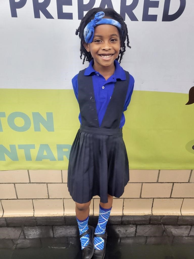 A child standing in front of a wallDescription automatically generated